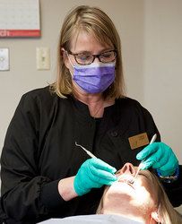 Female dentist performing dental care for patient